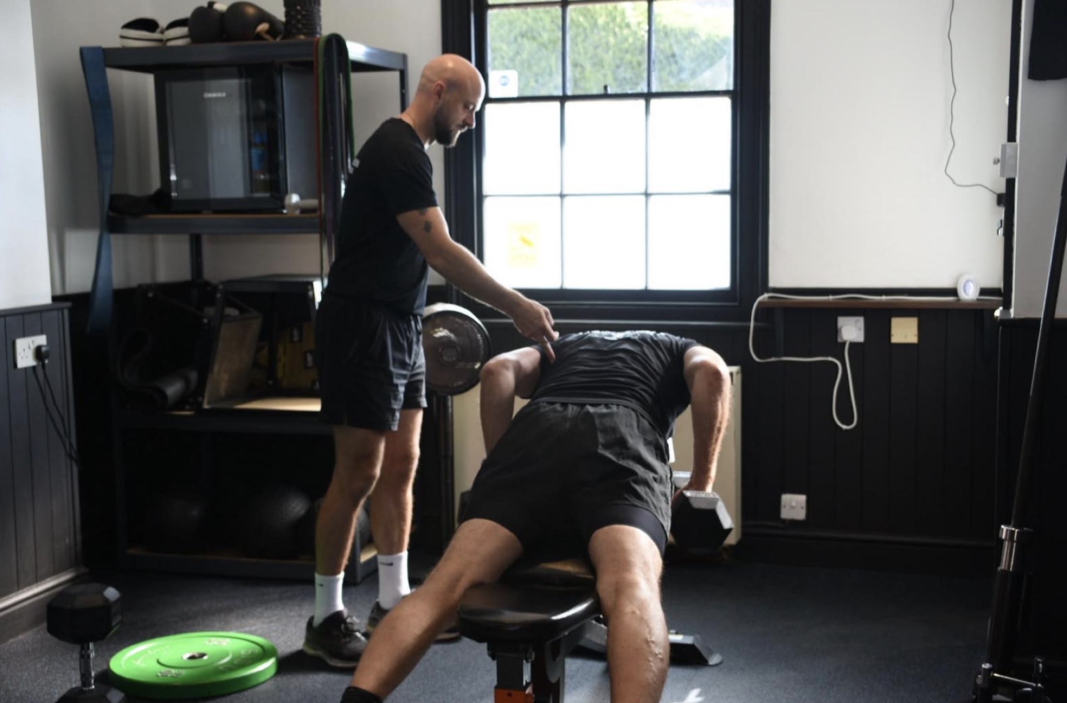 Michael Dennison coaching a client through a dumbbell row in his private studio